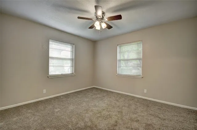 a view of an empty room and chandelier fan