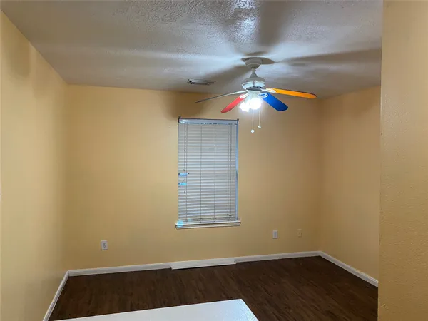 a view of an empty room with window and chandelier fan