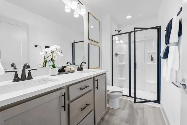 a bathroom with a double vanity sink toilet and shower