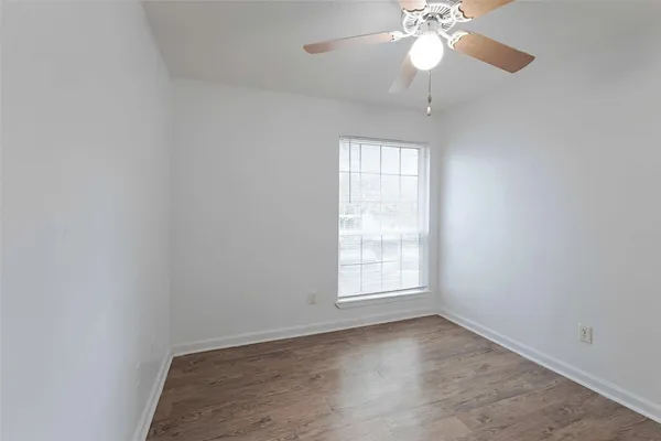 an empty room with a chandelier fan and windows