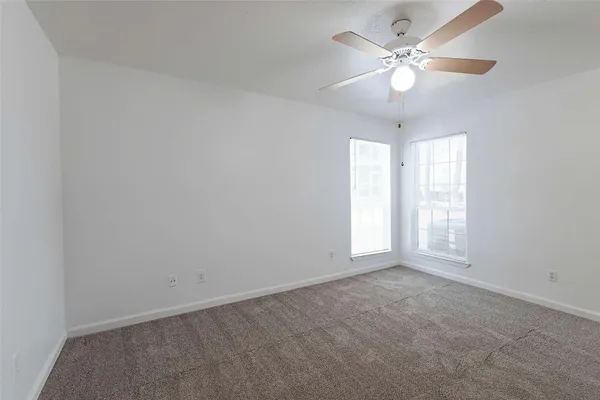 an empty room with a chandelier fan and windows