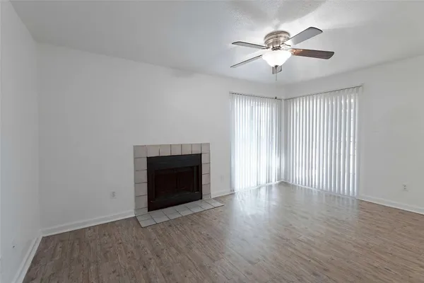 an empty room with wooden floor fireplace and windows