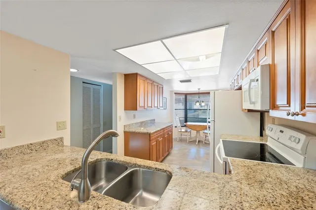 a kitchen with stainless steel appliances granite countertop a sink a stove top oven a dining table and chairs with wooden floor