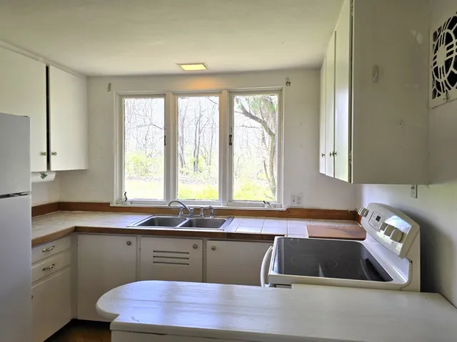 a kitchen with granite countertop a sink window and cabinets