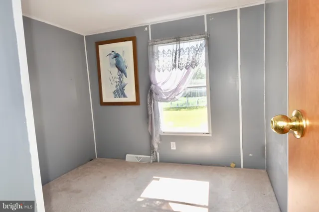 a view of an empty room with window and mirror