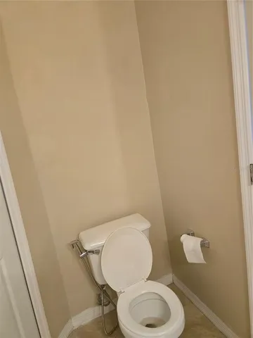 a white toilet sitting next to a white wall