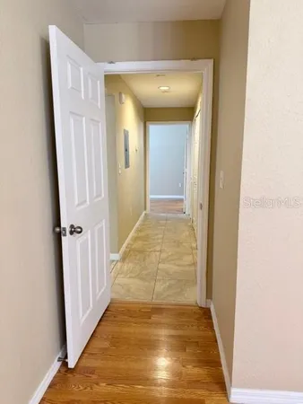 a view of a hallway with wooden floor and a bathroom