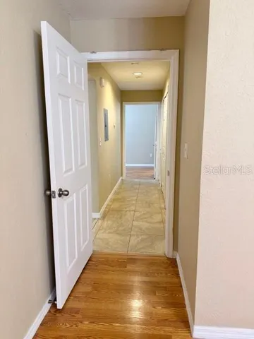 a view of a hallway with wooden floor and a bathroom