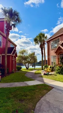 a view of a house with a big yard and palm trees