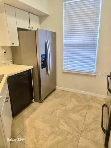 a view of a refrigerator in kitchen and an empty room