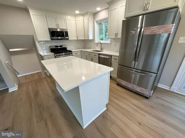 a kitchen with stainless steel appliances a refrigerator sink and wooden floor