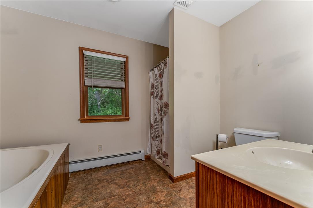 465 Raubsville Road Easton, PA 18042 - Photo 32 of 60 First floor primary bath A well-lit primary bathroom features a corner tub, window with verdant views, and a simple vanity.