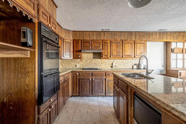 a kitchen with granite countertop a sink a counter space appliances and cabinets
