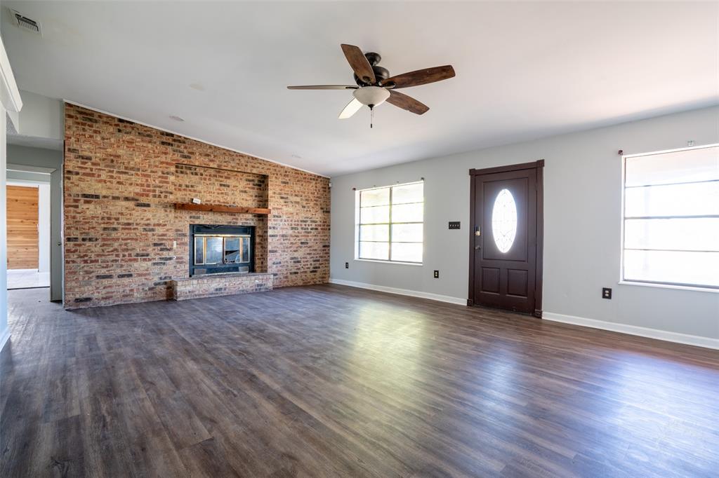 601 Henry Street Dublin, TX 76446 - Photo 4 of 40 an empty room with windows fireplace and wooden floor