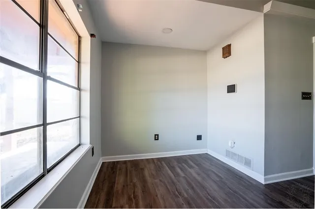 an empty room with wooden floor fireplace and windows