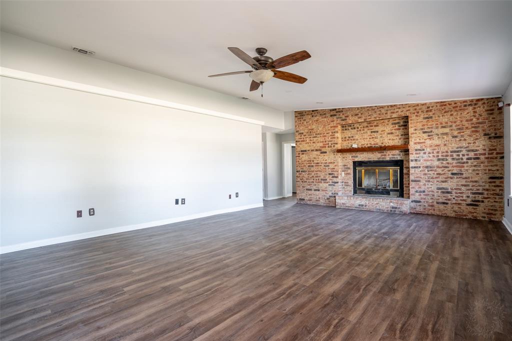 601 Henry Street Dublin, TX 76446 - Photo 7 of 40 an empty room with wooden floor fireplace and windows