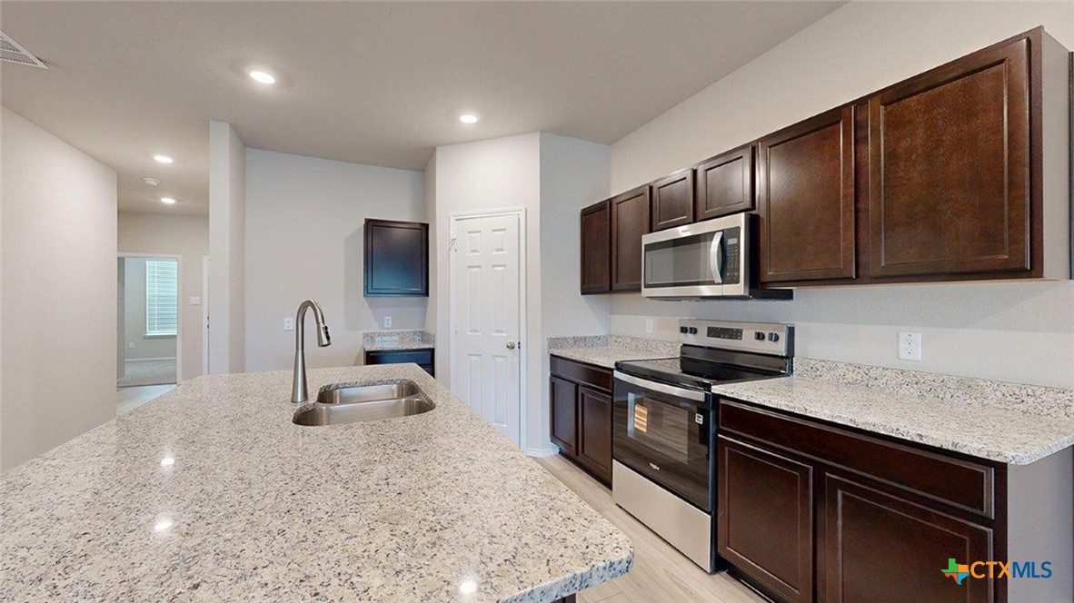 1111 Stone Vly Road Temple, TX 76502 - Photo 3 of 21 a kitchen with granite countertop stainless steel appliances and wooden cabinets