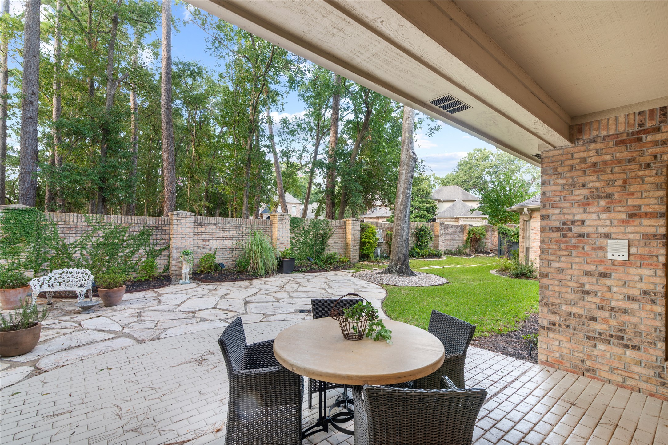 901 Longmire Road, Unit 51 Conroe, TX 77304 - Photo 45 of 48 Enjoy privacy with a brick wall and serene outdoor living with a spacious patio featuring elegant stone pathways, lush greenery.