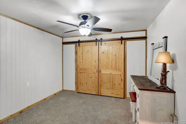 a view of a livingroom with a chandelier fan and wooden floor