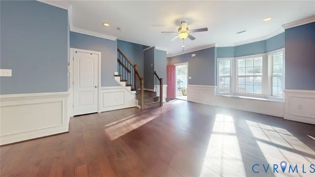 a view of an empty room with chandelier fan and wooden floor