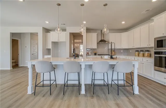 a kitchen with stainless steel appliances granite countertop a dining table chairs refrigerator and cabinets