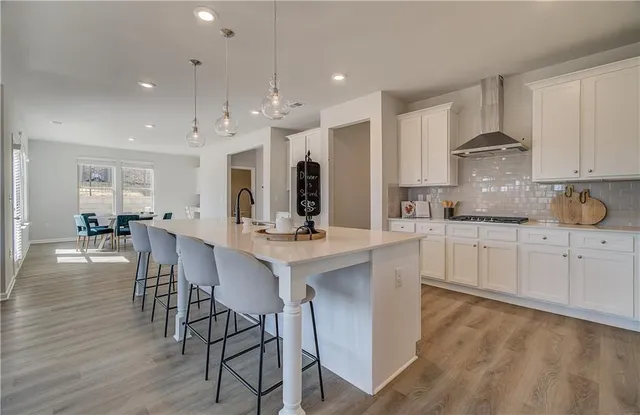 a kitchen with stainless steel appliances kitchen island granite countertop a table chairs sink and cabinets