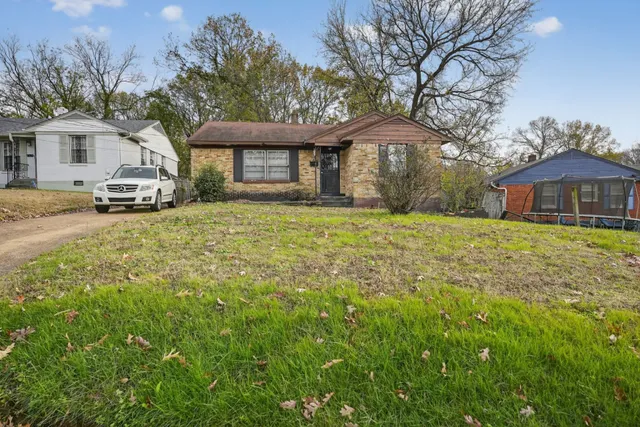 a front view of a house with a garden and trees