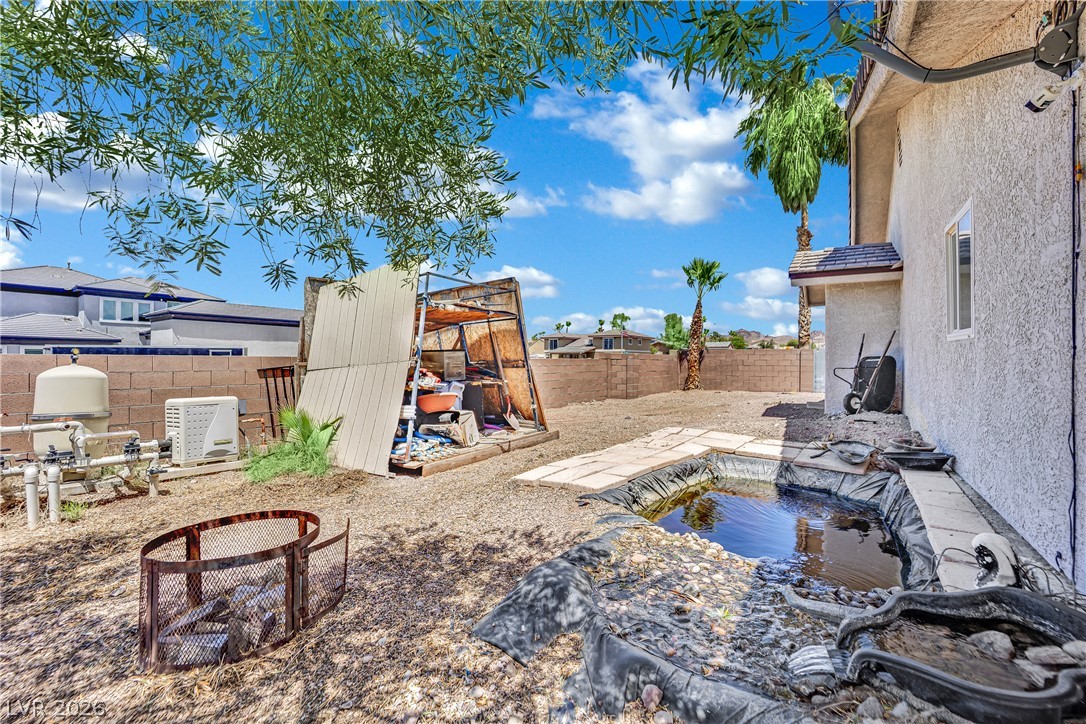 420 North Racetrack Road Henderson, NV 89015 - Photo 47 of 52 An arid desert landscape frames a spacious backyard with a pond feature, offering a refreshing outdoor retreat.