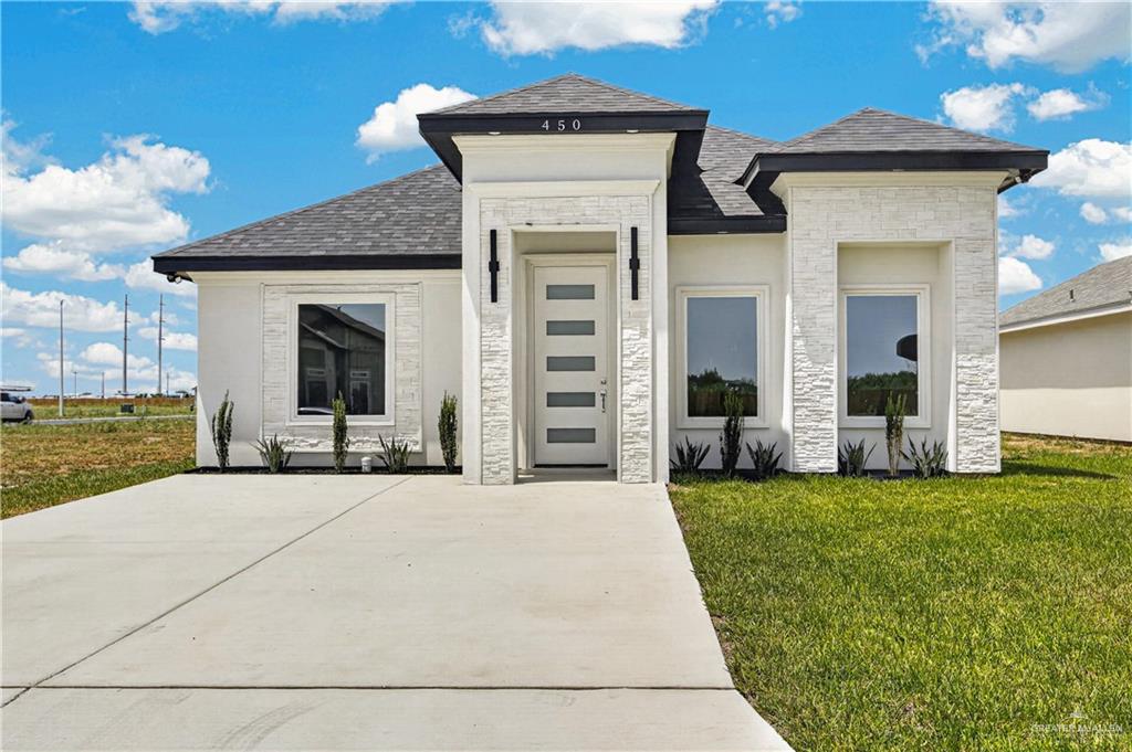450 Sandy Road Donna, TX 78537 - Photo 1 of 15 Contemporary exterior with white stucco finish, decorative stone accents, dark shingles, an inset entry, and a concrete driveway