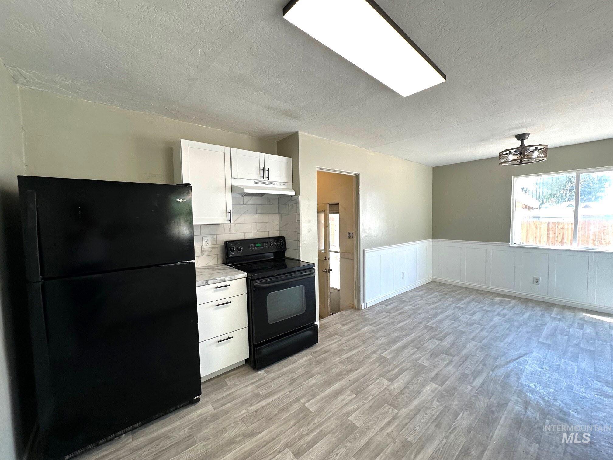 264 Southwest 10th Avenue Ontario, OR 97914 - Photo 7 of 29 Kitchen with black appliances, a textured ceiling, light wood-style flooring, white cabinetry, and light countertops