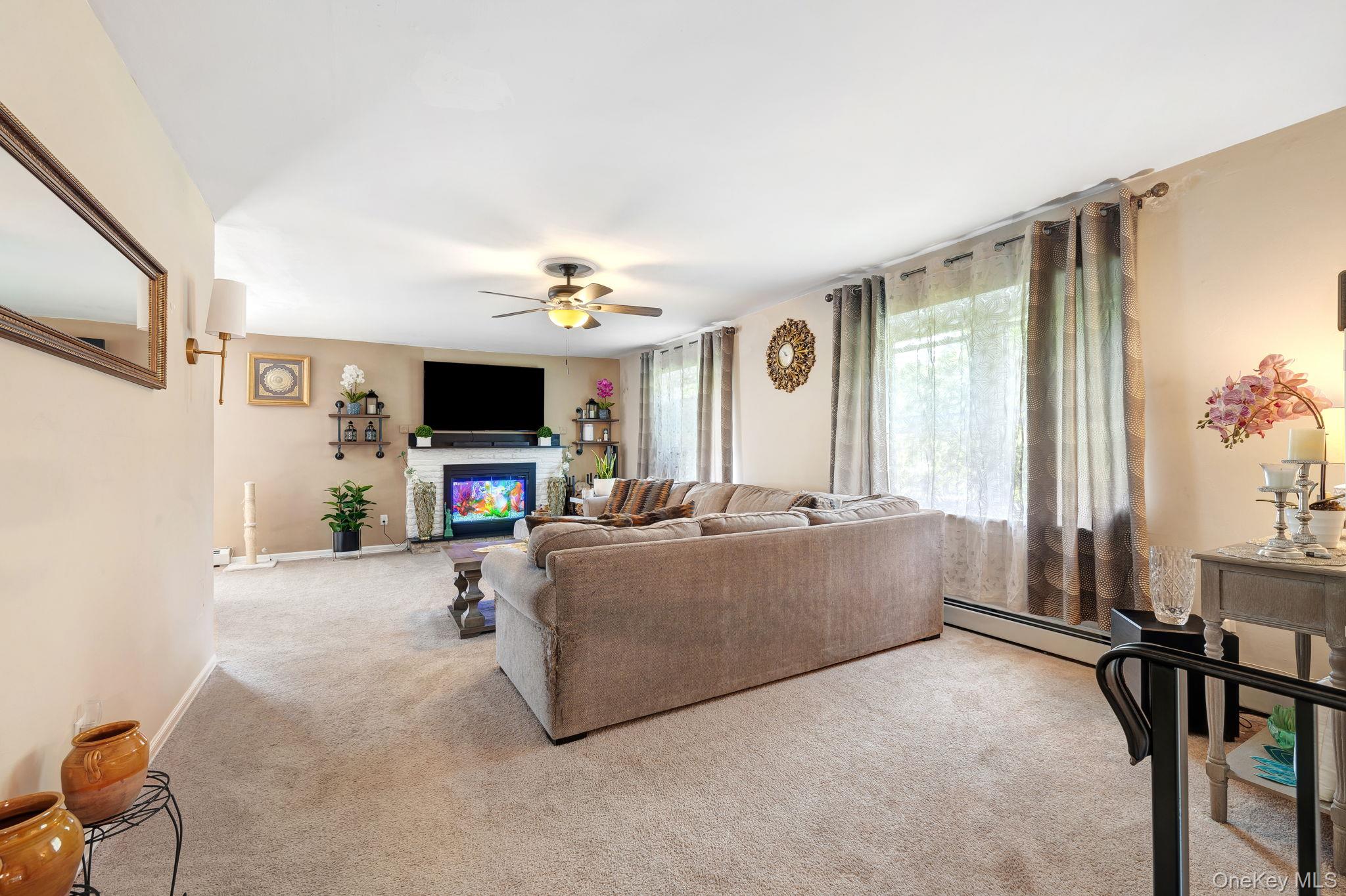 6 Farmstead Road New Windsor, NY 12553 - Photo 11 of 32 Living room featuring light carpet, a glass covered fireplace, baseboard heating, and a ceiling fan