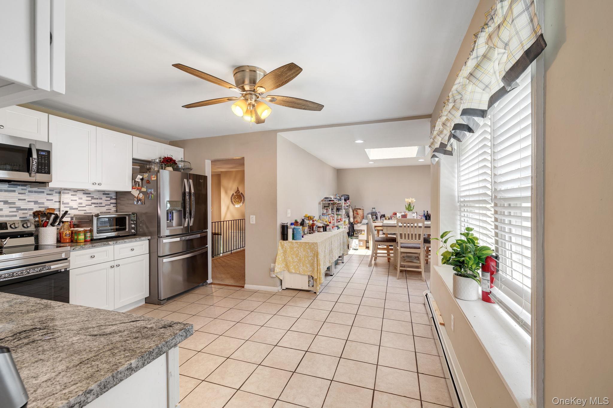 6 Farmstead Road New Windsor, NY 12553 - Photo 12 of 32 Kitchen featuring a skylight, white cabinetry, stainless steel appliances, and a baseboard heating unit