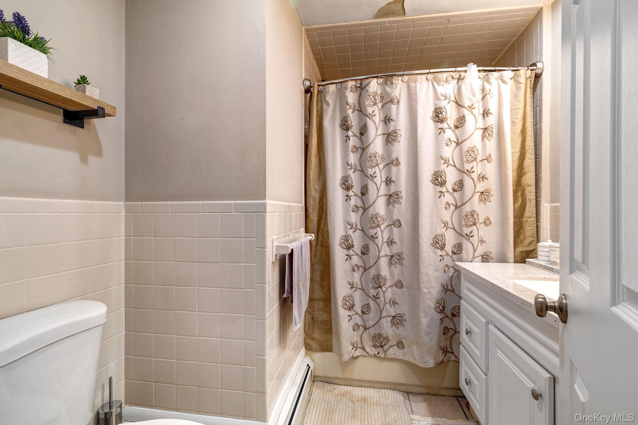 6 Farmstead Road New Windsor, NY 12553 - Photo 19 of 32 Full bathroom featuring vanity, tile walls, a baseboard heating unit, and shower / bathtub combination with curtain