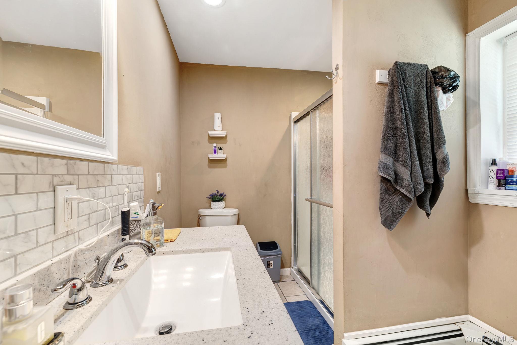 6 Farmstead Road New Windsor, NY 12553 - Photo 22 of 32 Full bathroom with decorative backsplash, a shower stall, light tile patterned floors, baseboard heating, and vanity