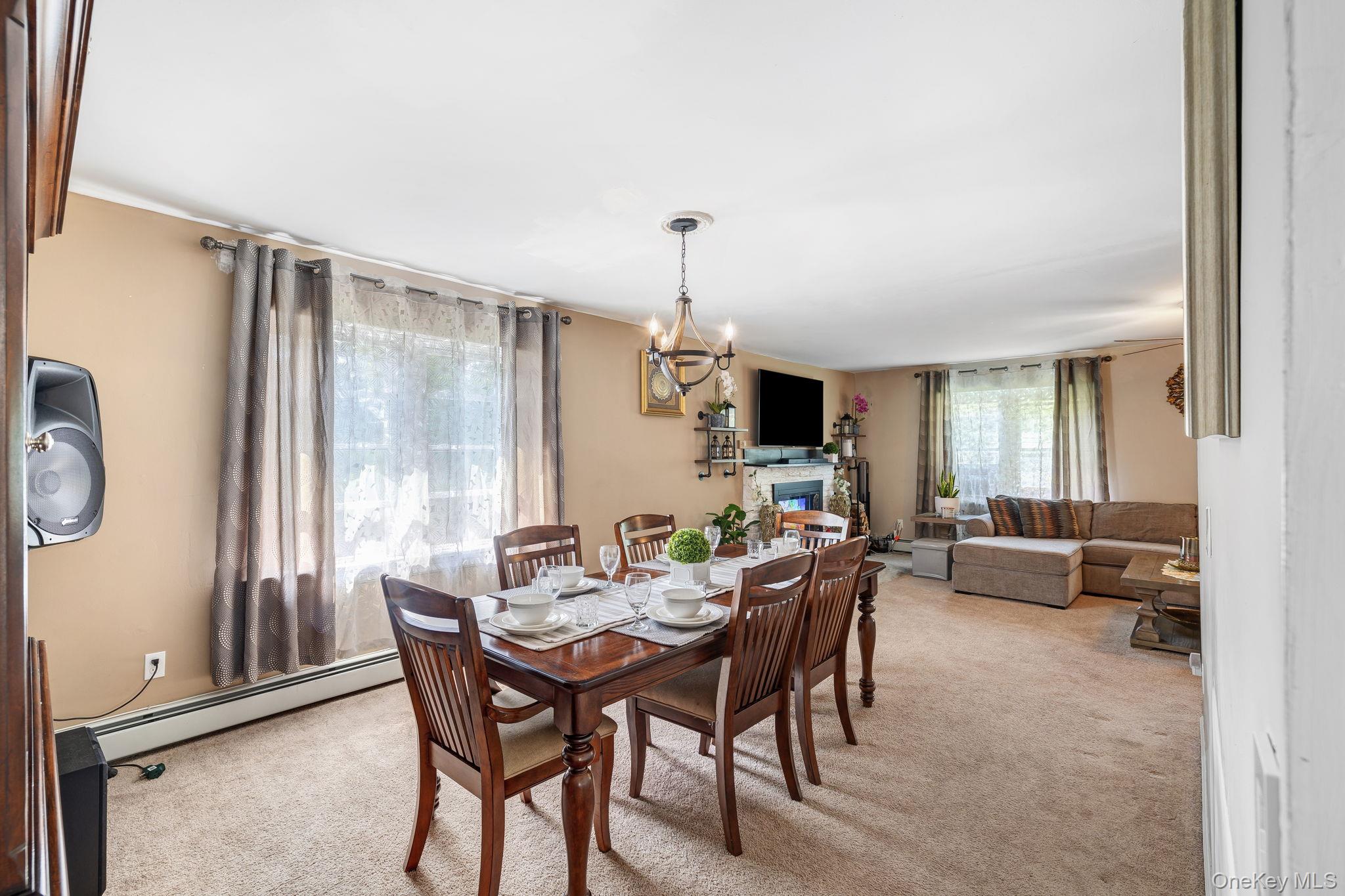6 Farmstead Road New Windsor, NY 12553 - Photo 9 of 32 Dining area with light carpet, a chandelier, a glass covered fireplace, and a baseboard radiator