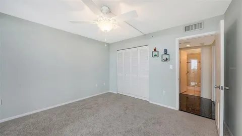 an empty room with closet and a ceiling fan