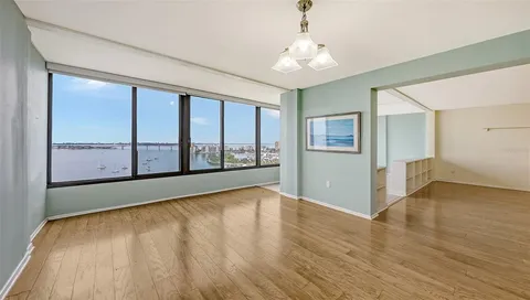 a view of an empty room with a window and wooden floor