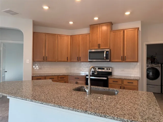 a kitchen with stainless steel appliances granite countertop a sink refrigerator and cabinets