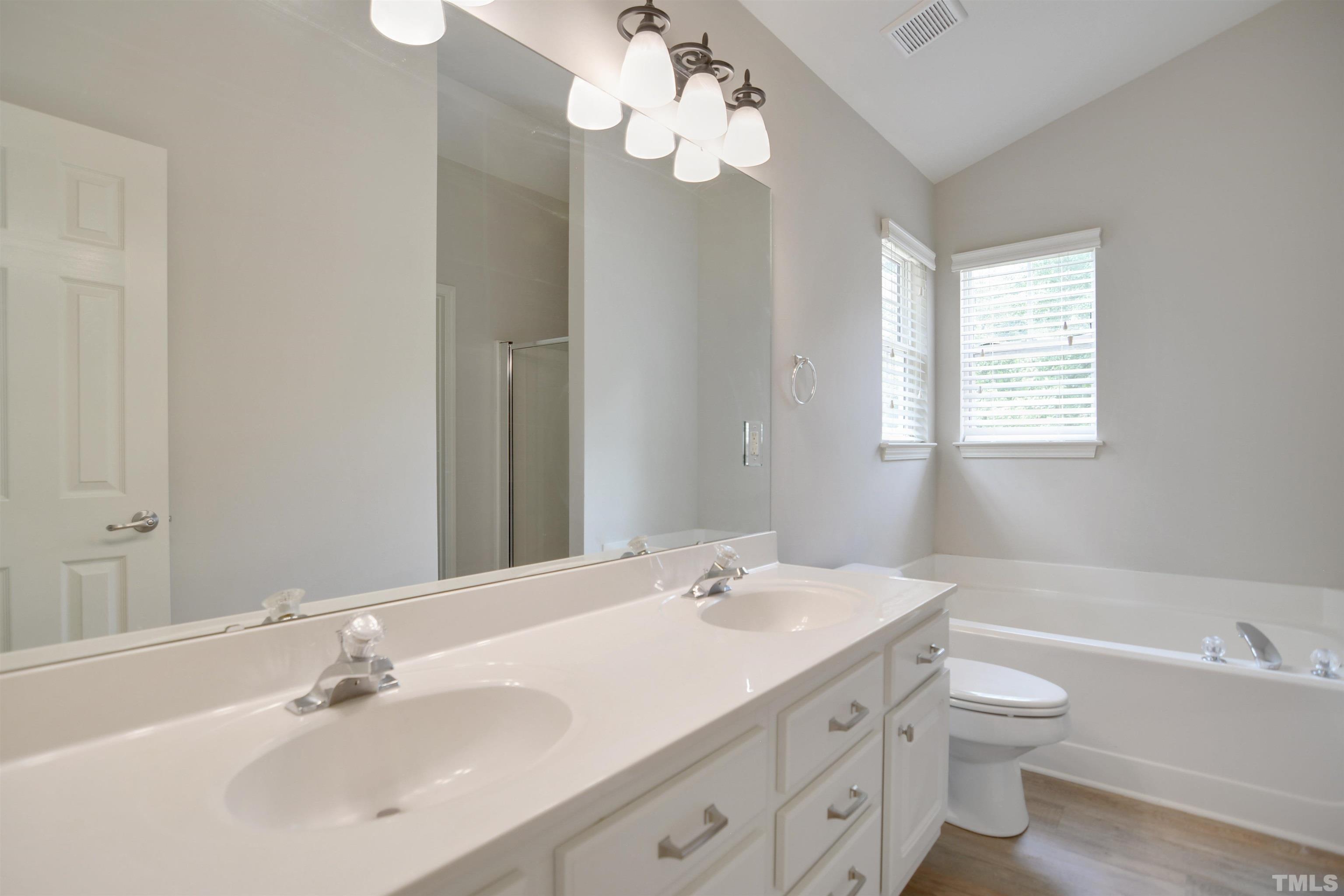 8400 Astwell Court Raleigh, NC 27615 - Photo 13 of 21 a bathroom with a double vanity sink a toilet and a mirror