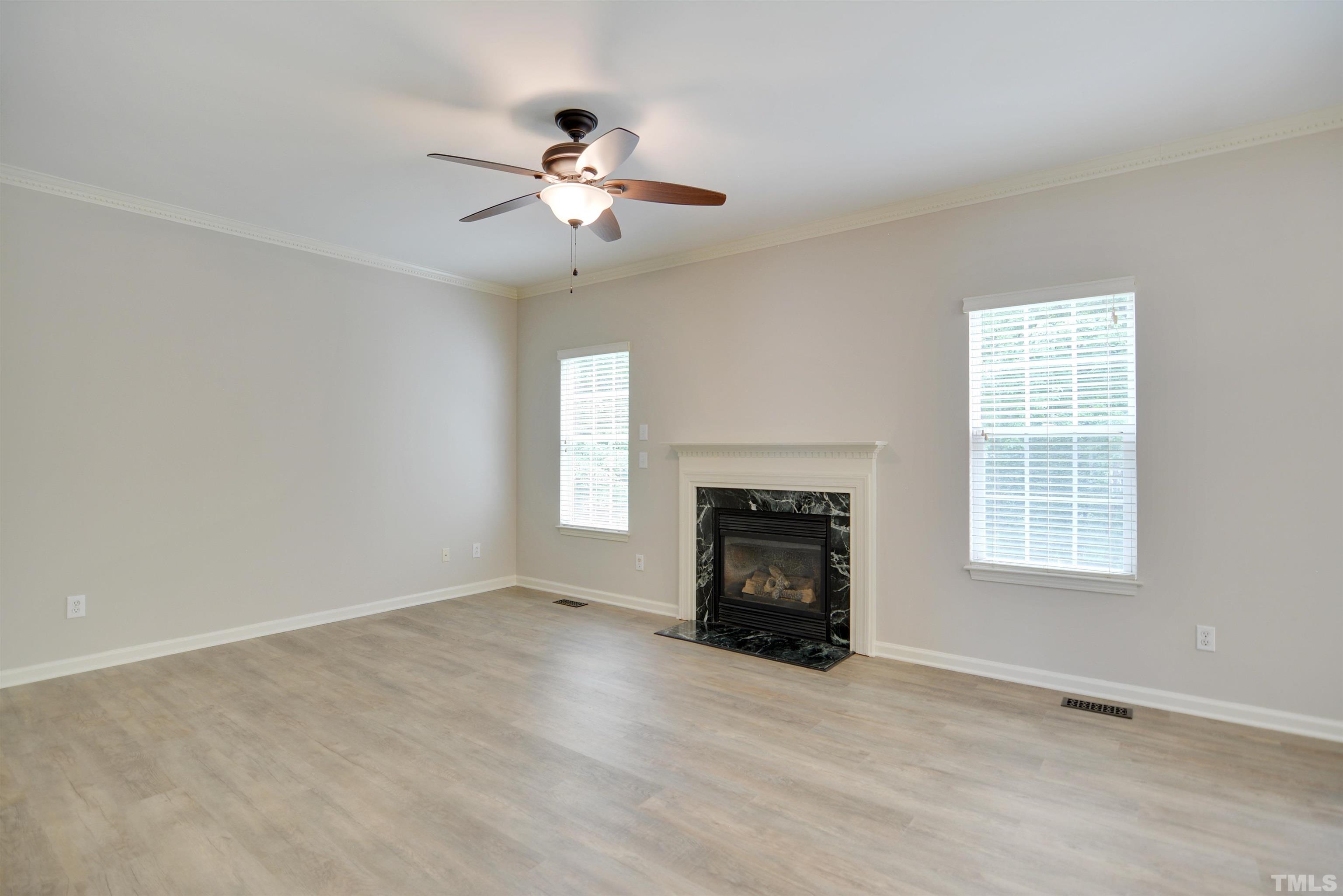 8400 Astwell Court Raleigh, NC 27615 - Photo 5 of 21 an empty room with windows fireplace and fans