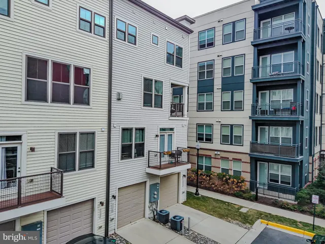 a front view of a building with glass windows and plants