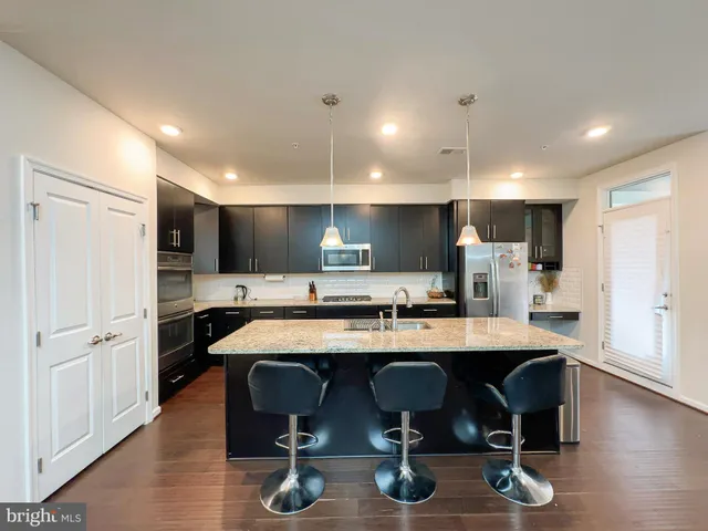 a kitchen with stainless steel appliances granite countertop a table chairs sink refrigerator and cabinets