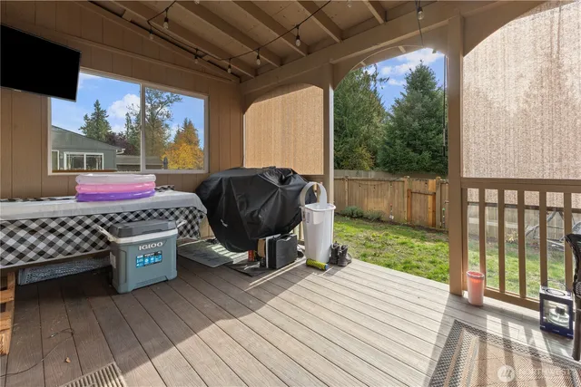 a view of a deck with wooden floor and roof with a garden view