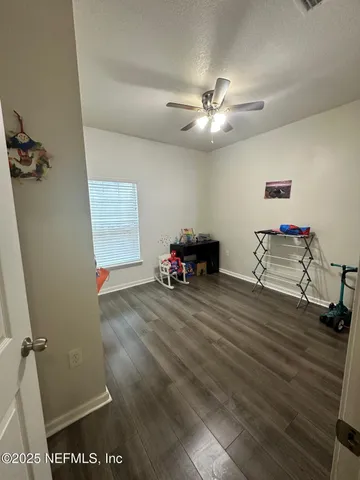 a view of empty room with wooden floor and fan