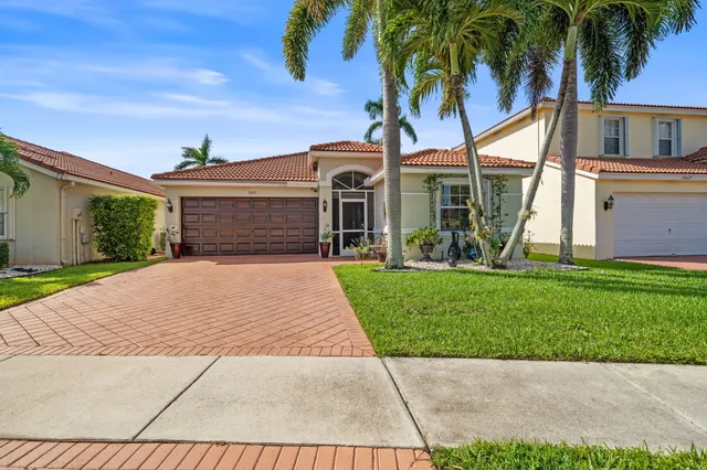 front view of a house with a yard and palm trees