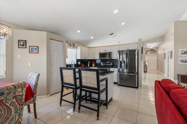 a kitchen with stainless steel appliances kitchen island granite countertop a refrigerator and a dining table