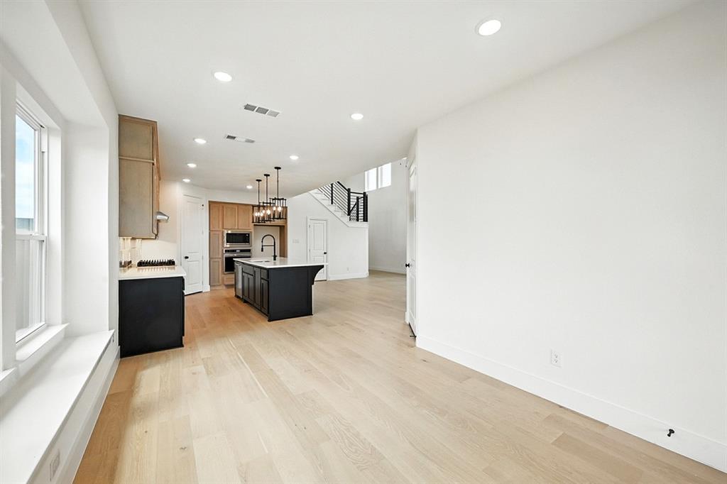 4520 Script Street Prosper, TX 75078 - Photo 22 of 27 a large white kitchen with a large kitchen island a stove a sink dishwasher and a refrigerator with wooden floor