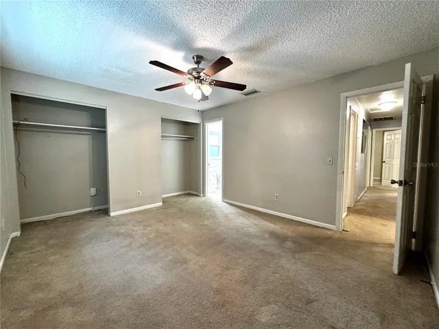 an empty room with chandelier fan and windows