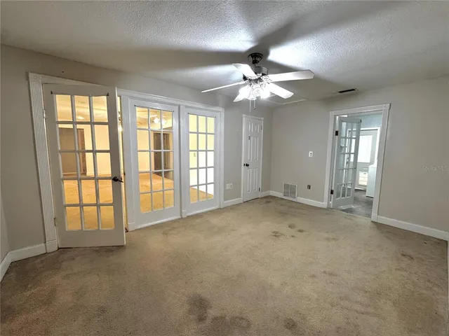 a view of a livingroom with a chandelier fan and windows
