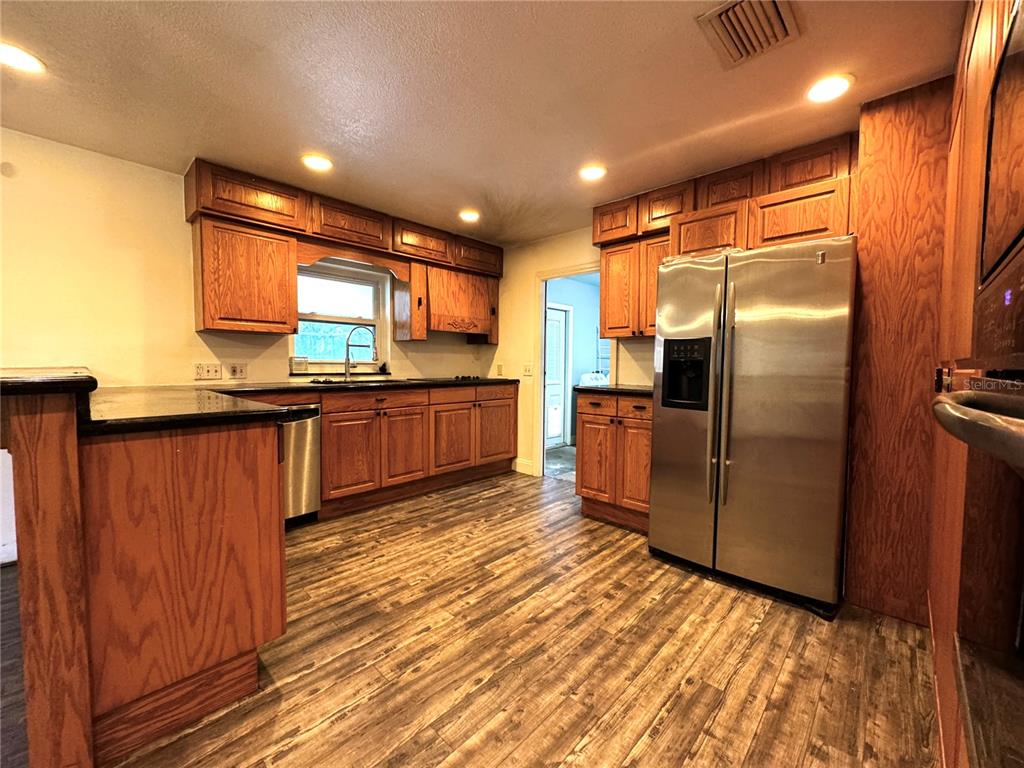 3419 Pearson Road Valrico, FL 33596 - Photo 5 of 20 a kitchen with stainless steel appliances granite countertop a refrigerator a sink dishwasher and wooden cabinets with wooden floor